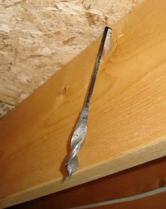 Looking up at drill bit and joist from garage