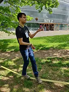 A Wikimedia Hackathon attendee standing on a rope while juggling.