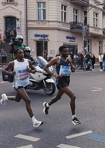 World record winner Tigst Assefa (left) about 25&nbsp;km (16&nbsp;mi) into the 2023 Berlin Marathon, alongside pacemaker Girmay Birhanu Gebru