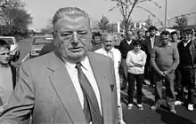 a man in a suit on the street while others look on