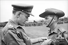 Black and white photograph of Brigadier (Oliver) David Jackson pinning the Military Cross on Harry Smith in military uniform, 1967