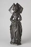 Figure G: Mourner with a linen truncated hennin. She has a v-shaped neckline, and wears a rose around her neck.