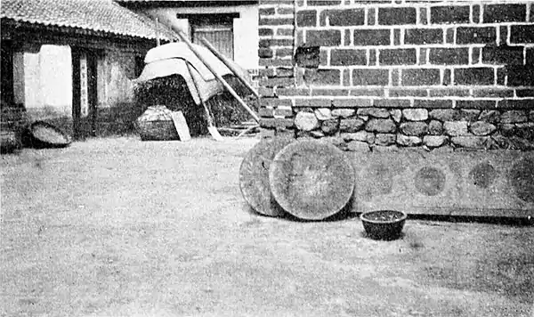 Farmers of forty centuries - Two large peanut cakes and a paper demijohn outside a village mill, Shantung, China.jpg