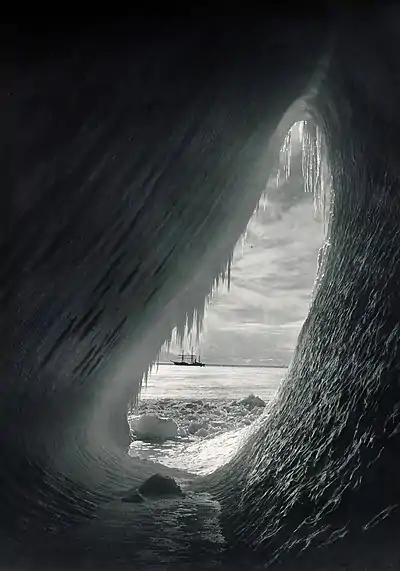Photo inside an elliptical ice tunnel looking out to a distant ship